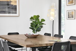 A dining area with a wooden table, black chairs, a decorative bowl, a potted plant, and a floor lamp. - Wye9 Beautiful Treetop And Beach Views Open (Wye River)