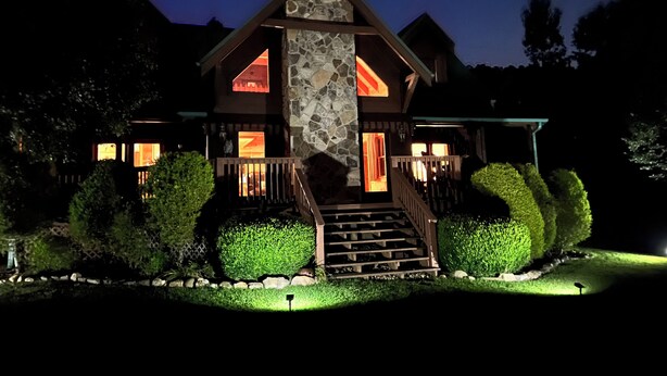 Una casa grande de varios pisos con chimenea de piedra, balcones de madera y una entrada principal bien iluminada.