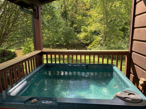 A hot tub on a wooden deck with a view of a lush garden and trees. - Beautiful Wears Valley Retreat, Amazing Views, Steps to Pool & Fishing Pond (Sevierville)