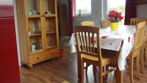 Un comedor con un mueble de madera, una mesa con sillas y una ventana con cortinas.