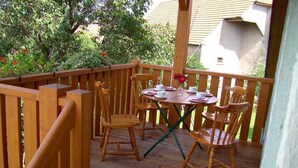Una terraza de madera con una mesa y sillas, rodeada por una barandilla de madera.