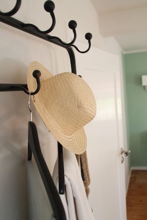 A hat hanging on a metal rack attached to a white door. - Tauberlodge (Creglingen)