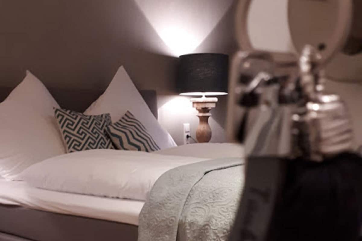 A bedroom with a bed, pillows, a bedside table with a lamp, and a keychain.