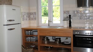 A kitchen with a white refrigerator, a Bosch oven, and a window with a view of greenery. - Tauberlodge (Creglingen)