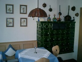 Una habitación con un aparador verde con motivos circulares, una lámpara de mimbre y cuadros en la pared.