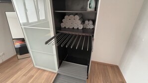 En modern garderob med ett inbyggt torkställ, hyllor för hopvikta handdukar och en liten strykbräda.