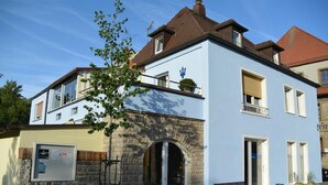 Un bâtiment à deux étages, doté d’une façade en pierre, d’un balcon et surplombant un ciel dégagé.
