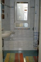 A bathroom with a bathtub, a sink, and a window.