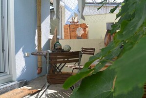 A patio area with a table and chairs, a potted plant, and a wooden crate with decorative items.