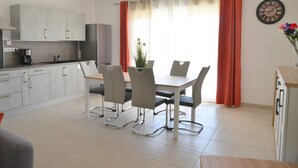 Una cucina moderna con mobili grigi, un tavolo da pranzo con quattro sedie e un orologio appeso al muro.