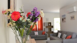 Un soggiorno con un divano grigio, un tavolino in legno e un vaso con fiori su un tavolino laterale.