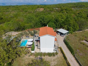 Ein Haus mit Schwimmbad, einer überdachten Terrasse und Blick auf einen bewaldeten Bereich.