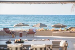 Un área de estar al aire libre con sombrillas, sillas y vista al mar.