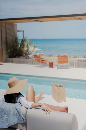 A person relaxing by a pool with a view of the ocean.