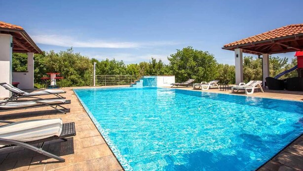 Une piscine avec des chaises longues et un espace abrité.