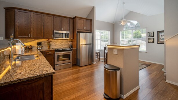 A modern kitchen with wooden cabinets, stainless steel appliances, and a granite countertop. - Luxury Golf Condo with Beautiful Course View from Sunroom (Branson)