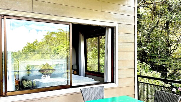 A balcony with wicker furniture, a table, and a view of greenery.