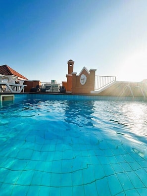 Una piscina techada, una piscina al aire libre, sombrillas