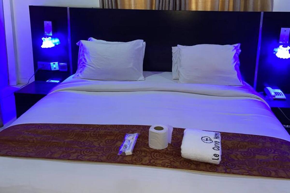 Habitación de hotel con cama, dos mesitas de noche con lámparas, aire acondicionado y una cortina.