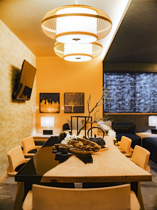 A modern dining area with a wooden table, chairs, and a hanging light fixture. - Samurai House 3 (Nagoya)