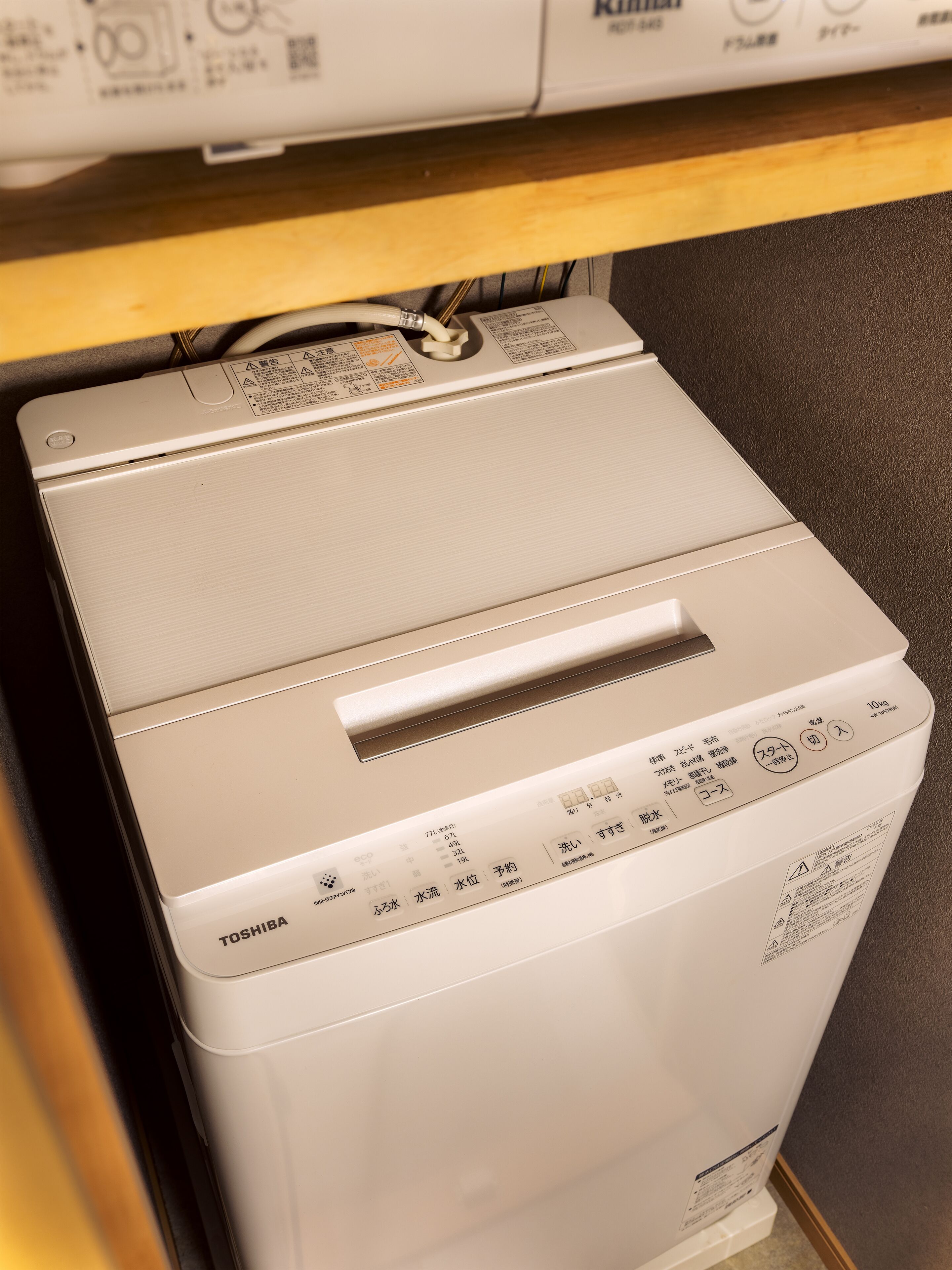 A white Toshiba washing machine with control panel and safety instructions.