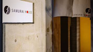 A sign for Samurai House, a building with a concrete exterior and a visible entrance.