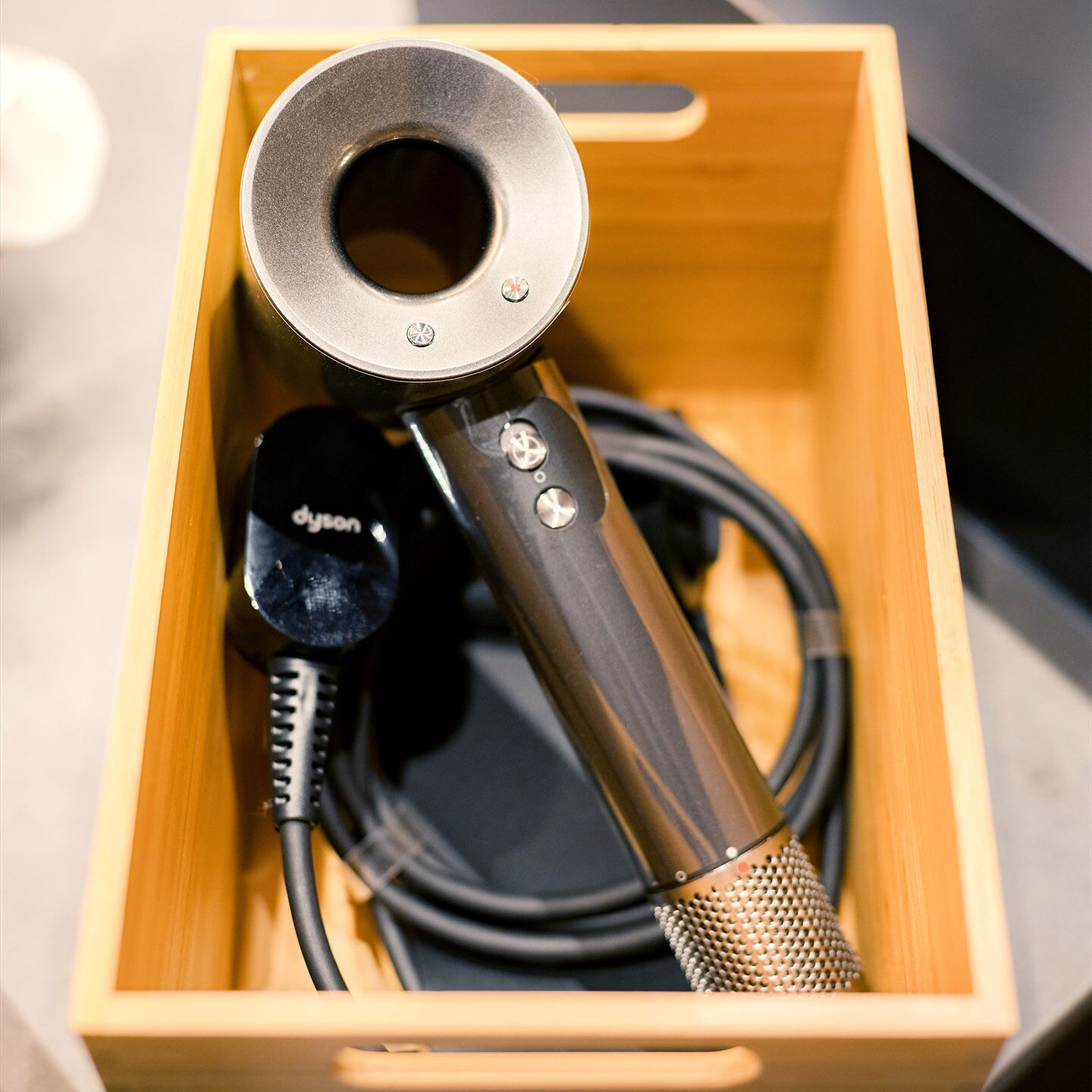 A microphone with a metal grille and a cable in a wooden box.