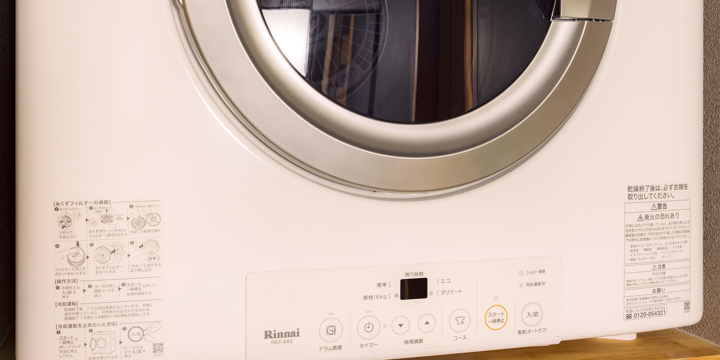 Et udvendigt billede af en hvid Rinnai RDT-54S vaskemaskine med kontrolpanel og brugsanvisning.