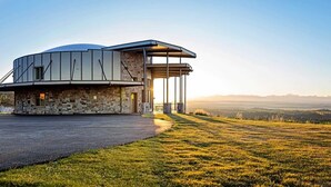 Un bâtiment moderne doté d’une façade en pierre et d’un grand espace ouvert devant l’entrée.
