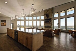 Eine geräumige Küche mit einer großen Kochinsel, Holzschränken und einer Wand mit Steinverkleidung.