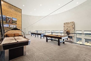 Amplio espacio interior con mesa de billar, mesa de fútbol de mesa y mesa de tiro. Varias áreas de estar y un ventanal con vistas al exterior.