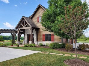 A two-story house with a stone foundation, red shutters, and a covered porch.
