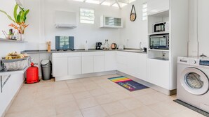 A modern kitchen with white cabinets, a built-in oven, and a washing machine.