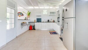 A modern kitchen with white cabinets, a stainless steel refrigerator, and a window with a view of greenery.