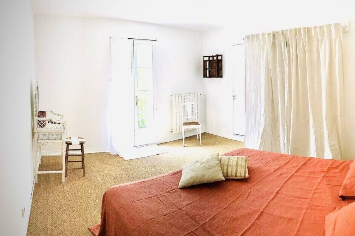 A bedroom with a bed, a chair, a small table, and a curtain.