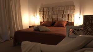 A bedroom with a large bed, two pillows, a nightstand, a wall-mounted light, and a chair. - Mas de l'Acacia (Tavel)