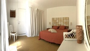 A bedroom with a large bed, a chair, a bedside table, a lamp, and a mirror. - Mas de l'Acacia (Tavel)