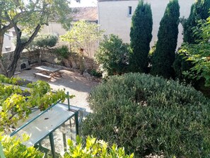 A garden with a stone wall, a wooden bench, and various shrubs. - Mas de l'Acacia (Tavel)