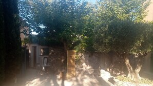 A stone wall with a wooden gate, a small table with a chair, and a bicycle parked nearby. - Mas de l'Acacia (Tavel)