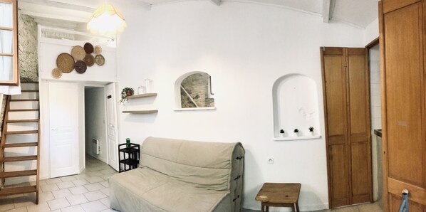 A living room with a sofa, a small table, a wooden door, and a staircase. - Mas de l'Acacia (Tavel)