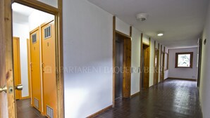 A hallway with wooden doors numbered 8 and 9, a window with a view, and a tiled floor. - Saburedo - Edificio Saumet (Baqueira)
