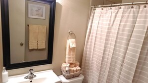 Une salle de bain équipée d’un lavabo, d’un miroir, de toilettes et d’un rideau de douche à rayures.
