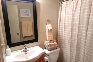 Een bad/douchecombinatie, handdoeken