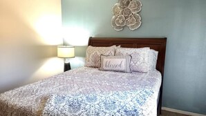 Une chambre à coucher avec une couvre-lit à motifs, un élément décoratif mural et une lampe de chevet.