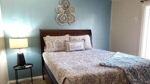 Une chambre à coucher avec un lit, une table de chevet, une lampe et un élément décoratif mural.