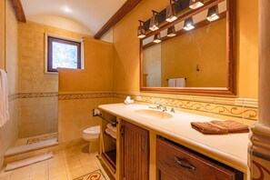 A bathroom with a large mirror, a sink, and a toilet.