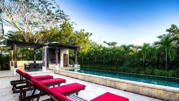 A pool area with red lounge chairs and a covered seating area. - Casa Orchidea (Tamarindo)