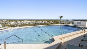 Une piscine à l’eau d’un bleu cristallin, entourée d’une terrasse carrelée et de chaises longues.