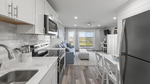 Une cuisine moderne avec des meubles blancs, un grand îlot central et une vue sur l’extérieur.