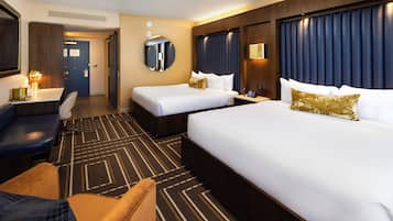 Ein Hotelzimmer mit zwei Betten, einem Schreibtisch, einem Stuhl und einem großen Spiegel.